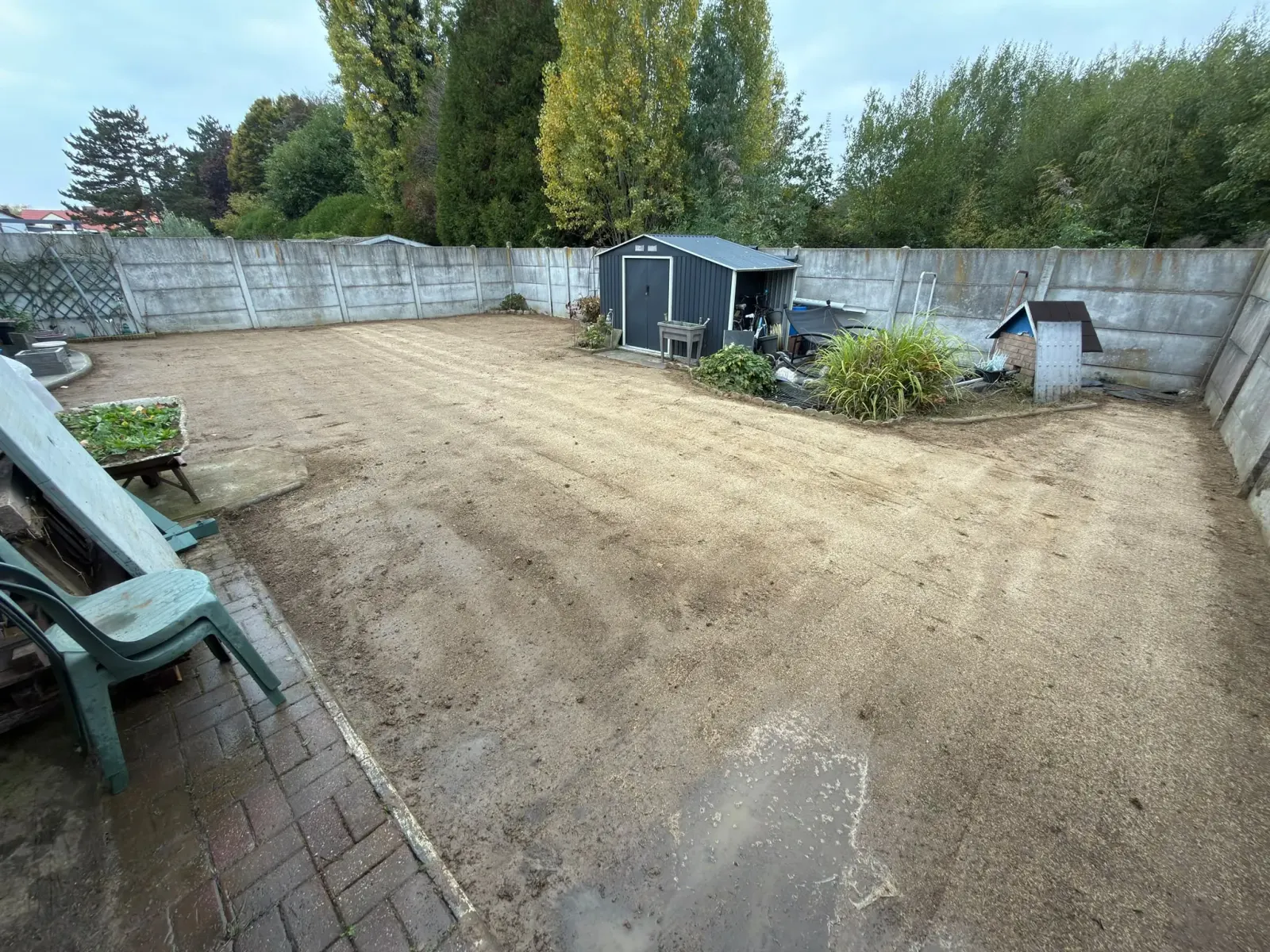 Renouvellement pelouse Lambersart : terre égalisée et ratissée, prête pour le semis, dans un jardin clos